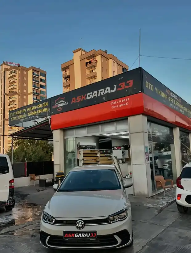 Ask Garaj 33'ün kırmızı tabelalı dükkânı ve önünde beyaz Volkswagen Polo